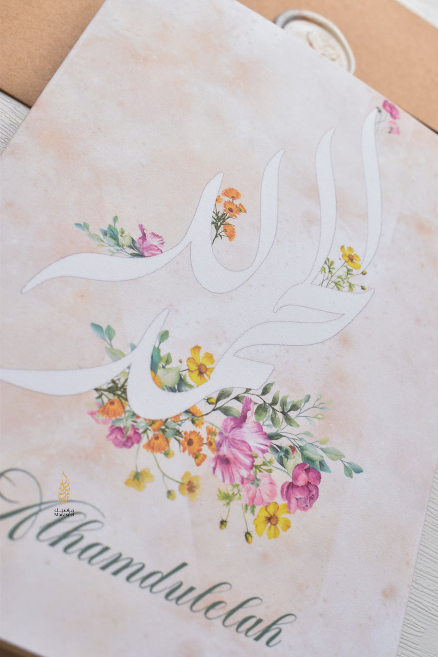 Card with calligraphy design for " Thank God or Alhamdulelah and a floral wreath on a brown envelope