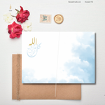 Load image into Gallery viewer, 
Open greeting card with soft sky-blue background and Arabic calligraphy, styled flat lay with red roses, white flowers, kraft envelope, and wax seal
