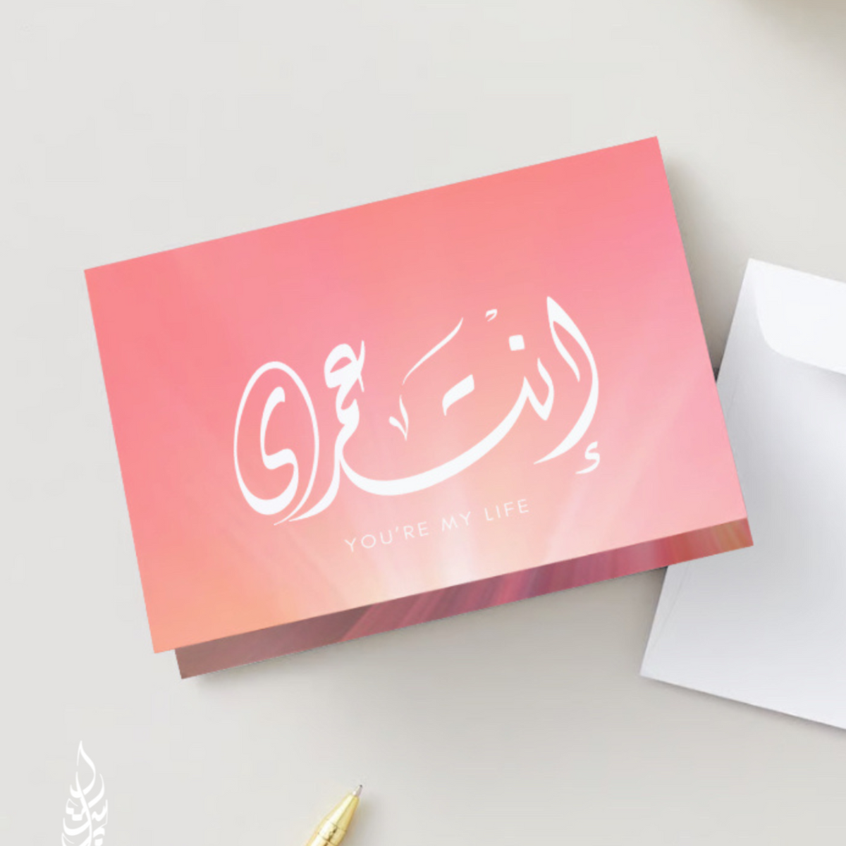 Pink box with white Arabic calligraphy on a light gray background