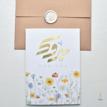 Greeting card with gold Arabic text and floral design on a white background
