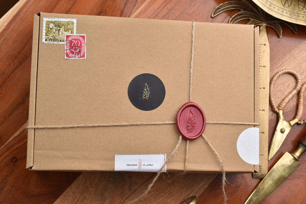 Maraseel card set box in kraft paper, tied with twine and closed with a red wax seal, with vintage stamps, on a wooden desk