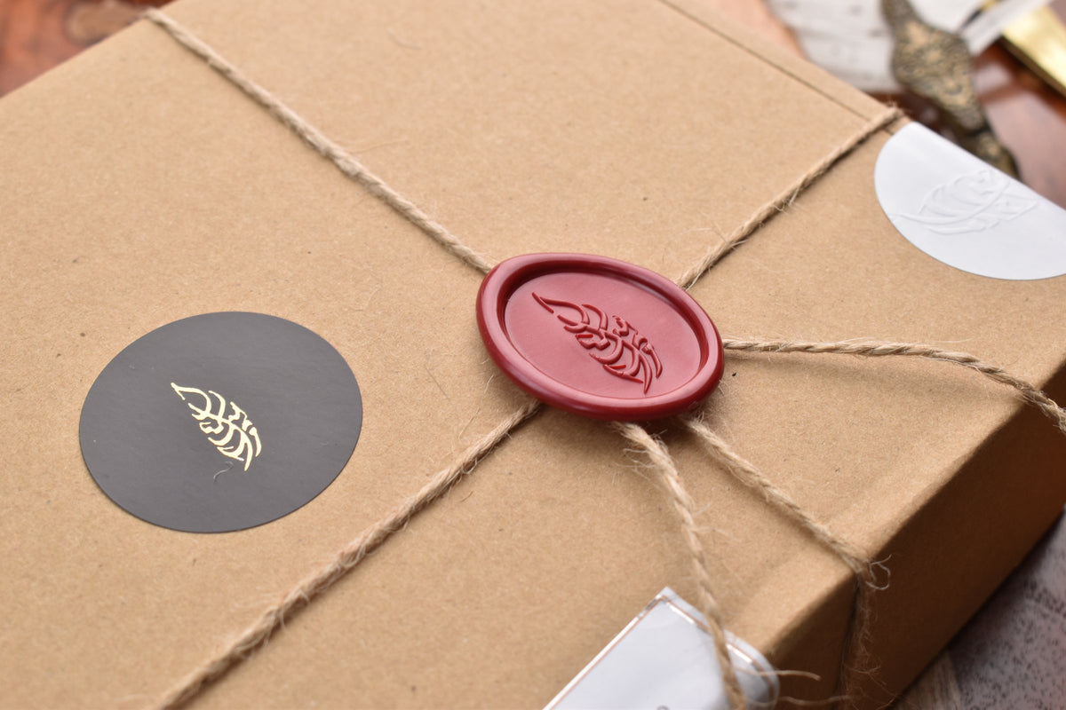 Close-up of the red Maraseel wax seal and gold leaf sticker on a card set box tied with twine