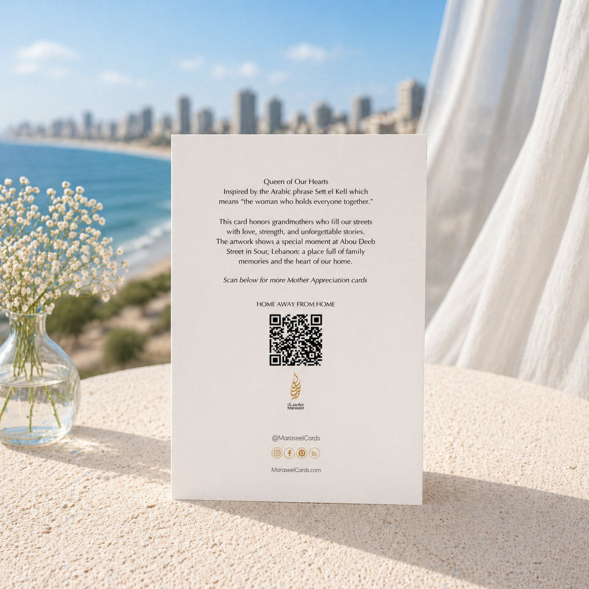Card with text and QR code on a sandy surface with flowers and cityscape in the background